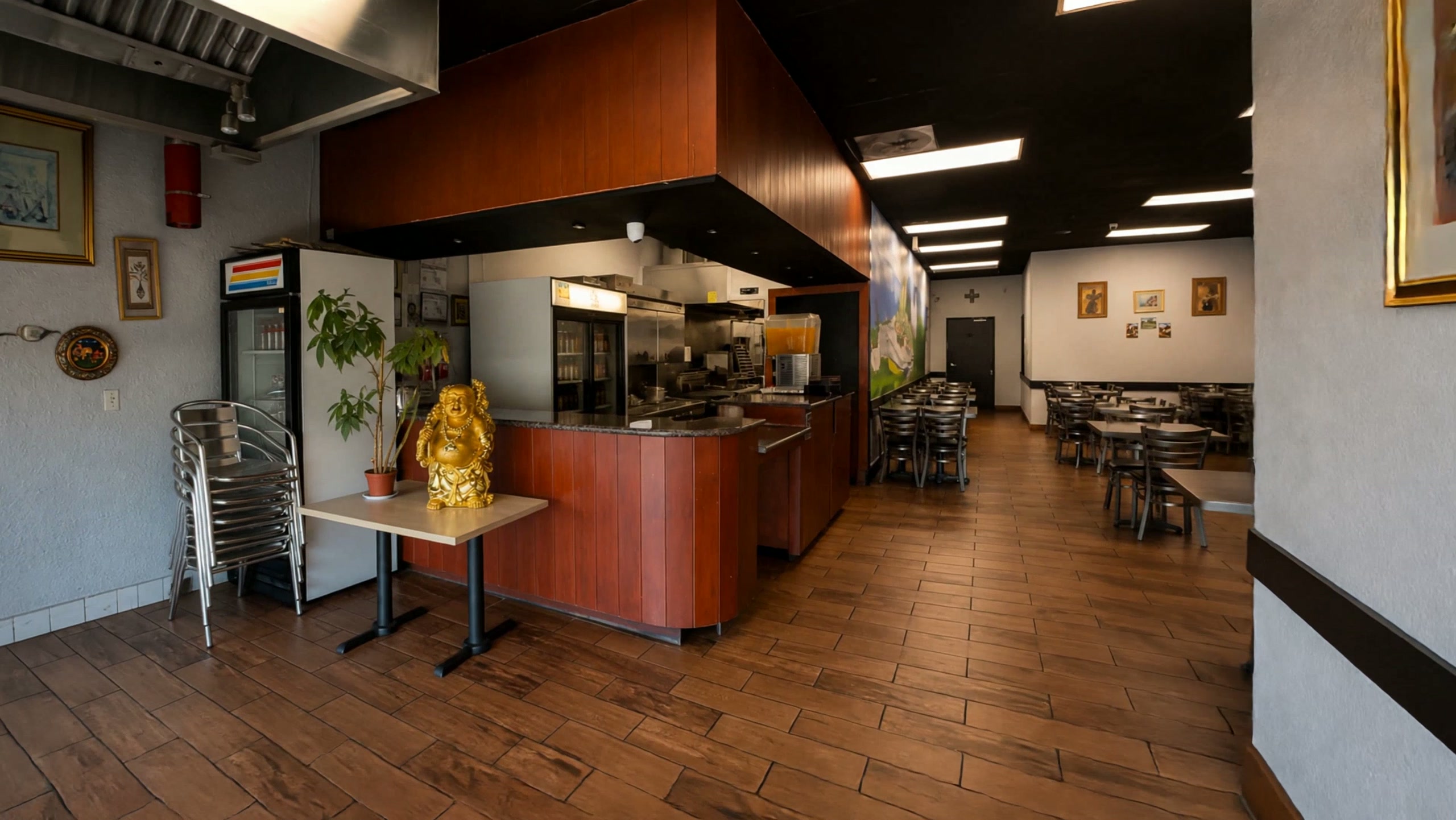 Inside Inti: the reddish-brown service counter with a gold Buddha statue and a plant, beneath a black ceiling, with the dining room beyond.